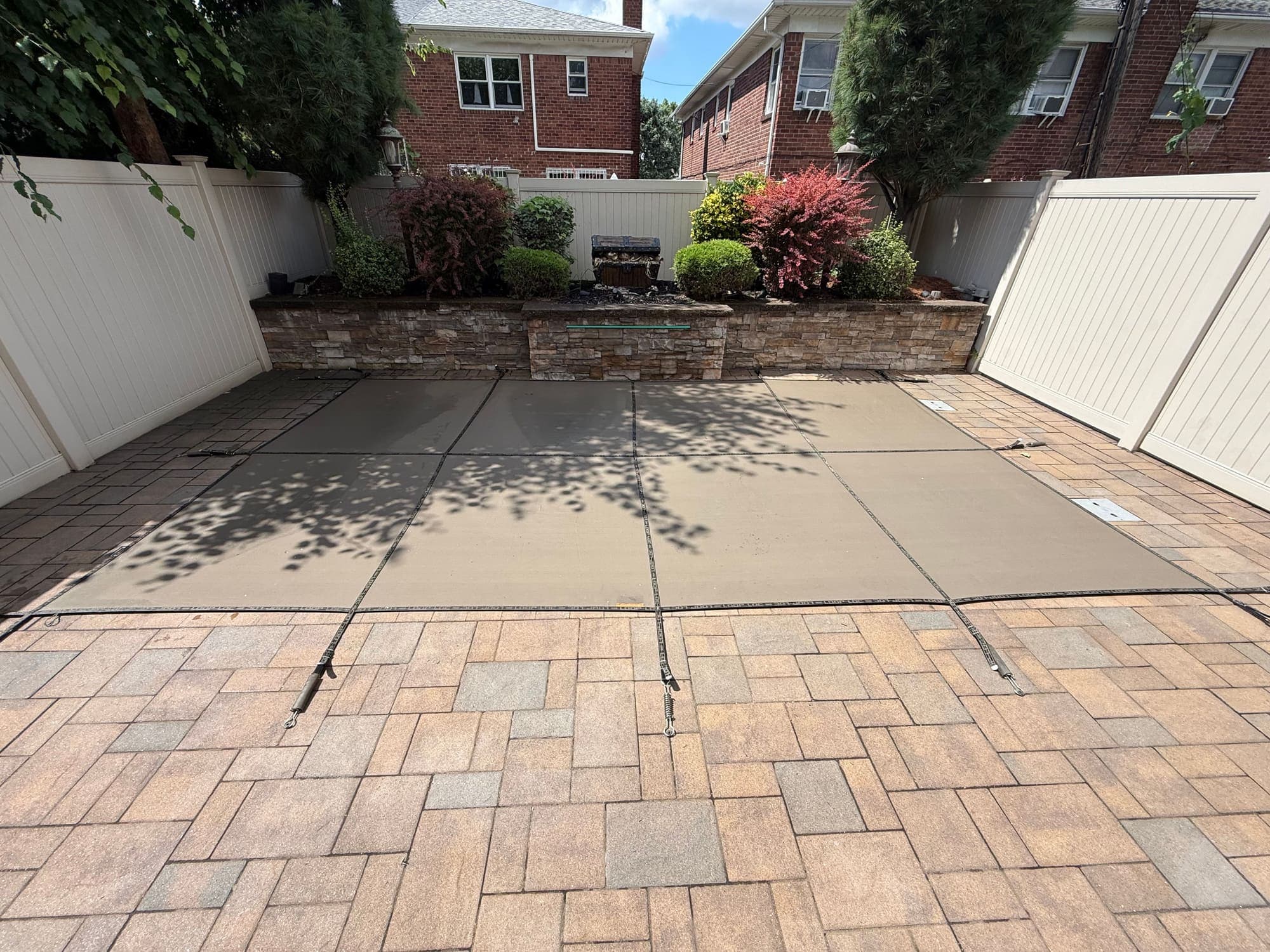 Safety cover strapped over a pool and anchored into the surrounding paver deck
