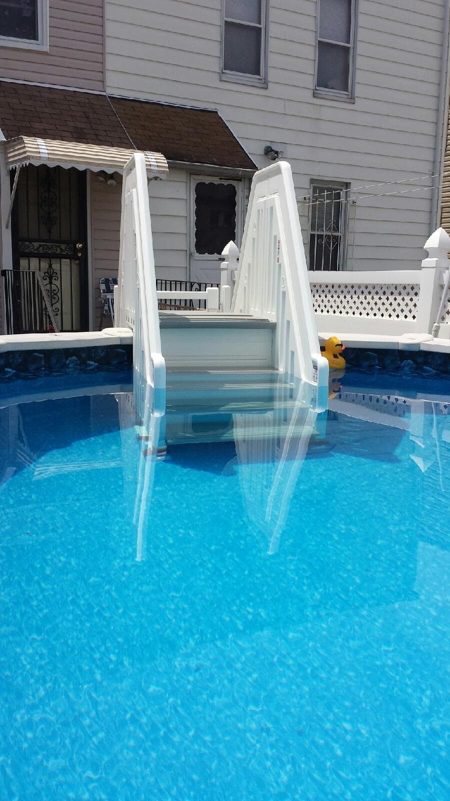 Entry steps head-on from the water, treads dropping below the waterline between two white handrails.