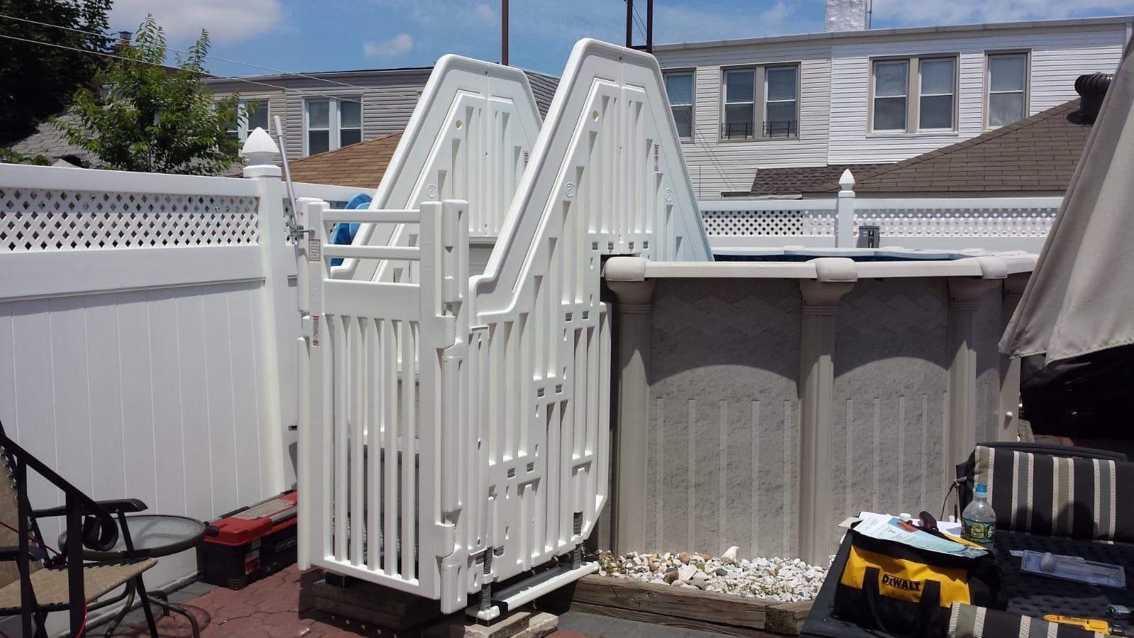 White entry system with the gate latched, photographed from the patio on install day with tools still out.
